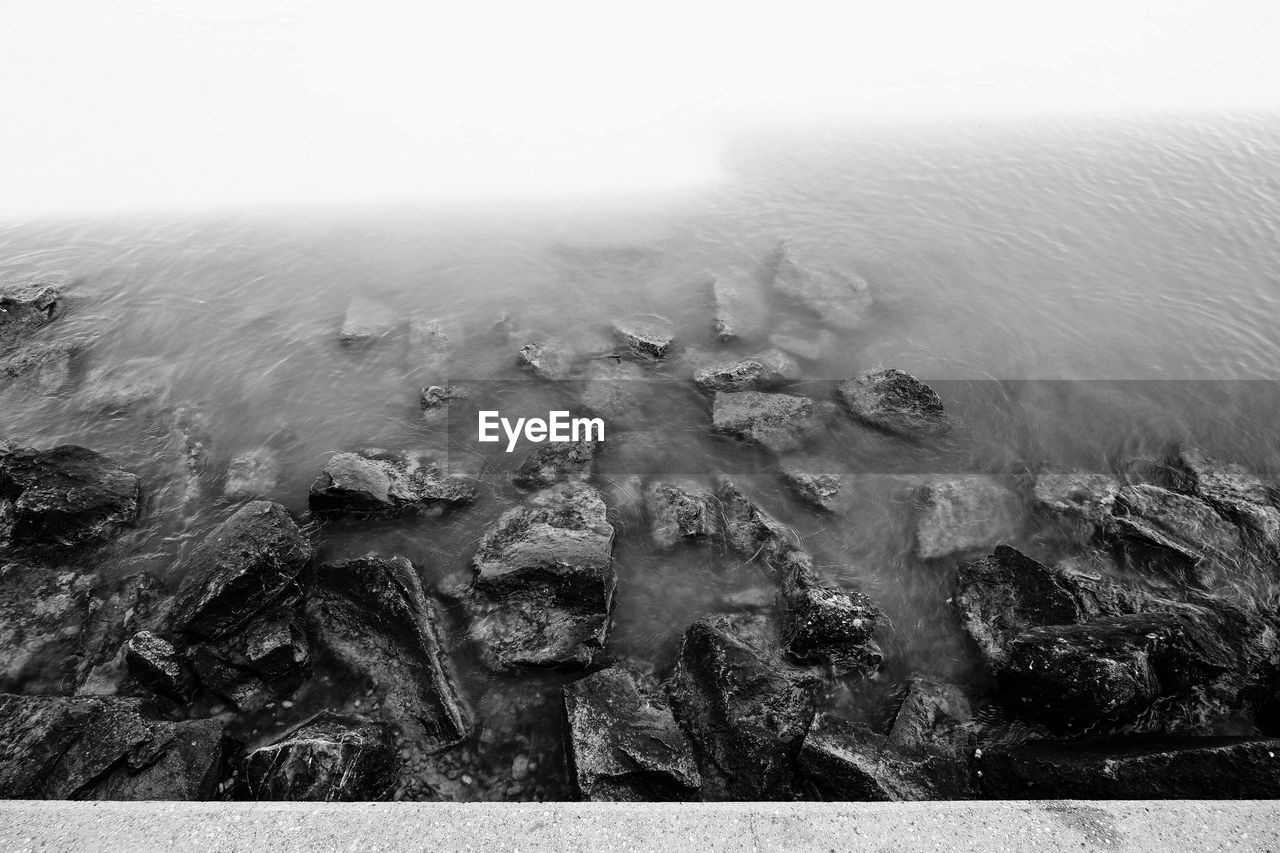 HIGH ANGLE VIEW OF ROCKS IN SEA