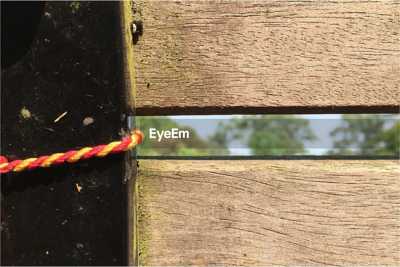 Close-up of thread tied to wooden fence