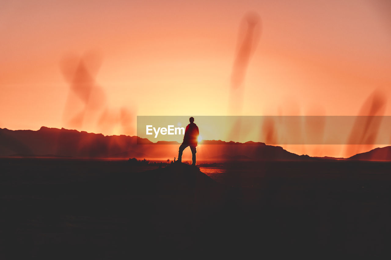 Silhouette man standing on mountain during sunset