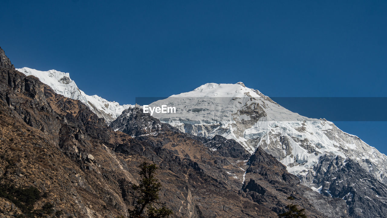 LOW ANGLE VIEW OF SNOWCAPPED MOUNTAIN AGAINST BLUE SKY