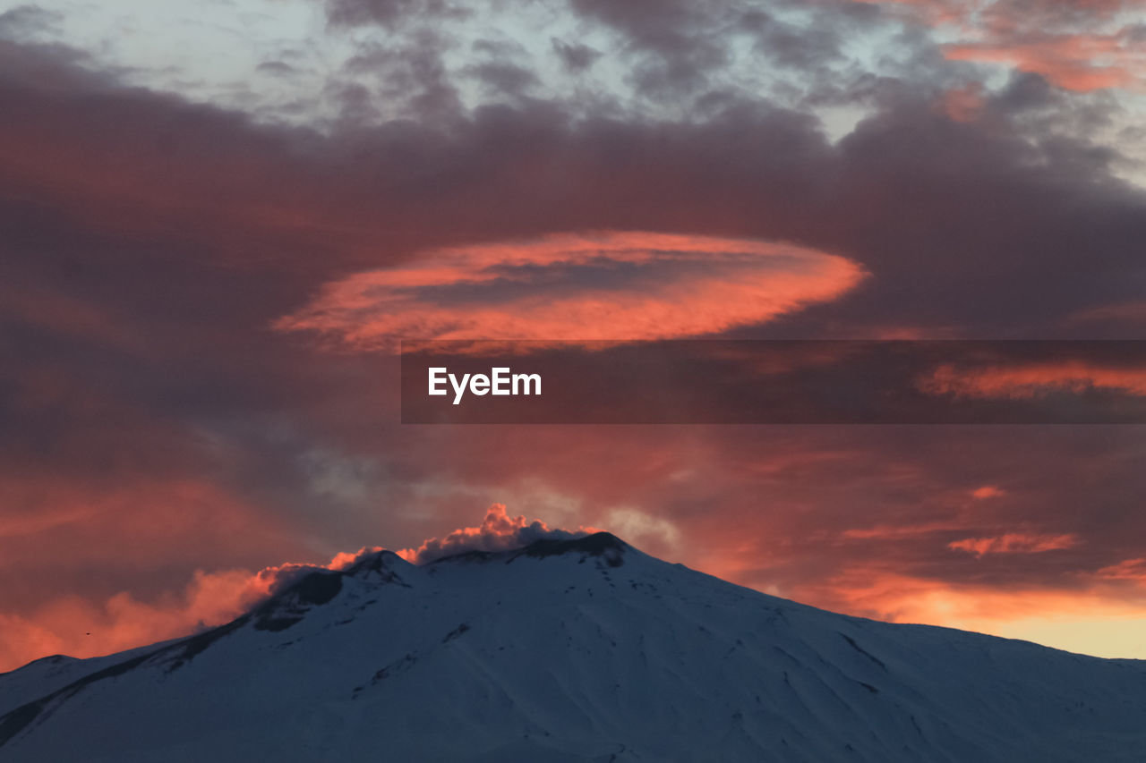 Scenic view of snowcapped mountain against cloudy sky during sunset