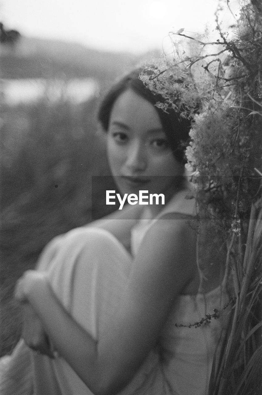 Portrait of bride sitting against plants