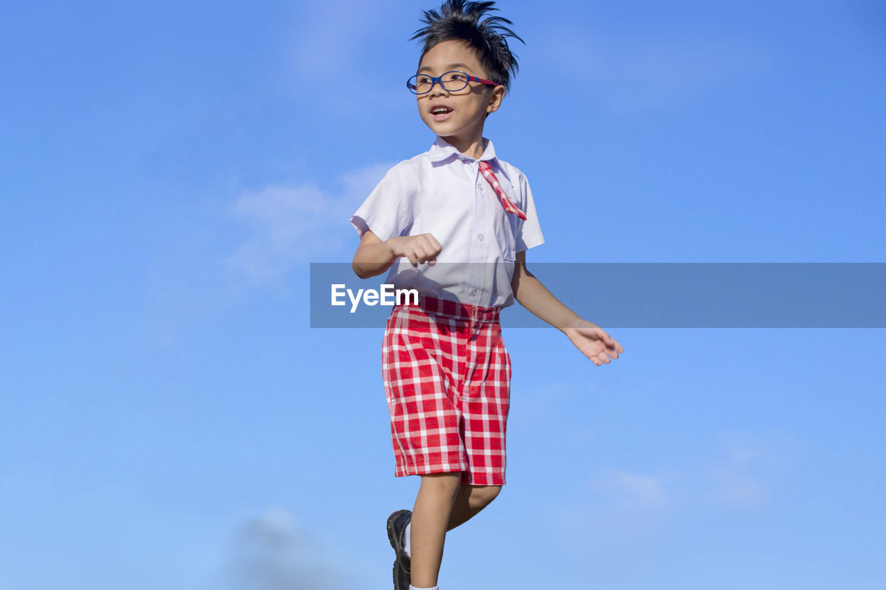 School boy standing against blue sky