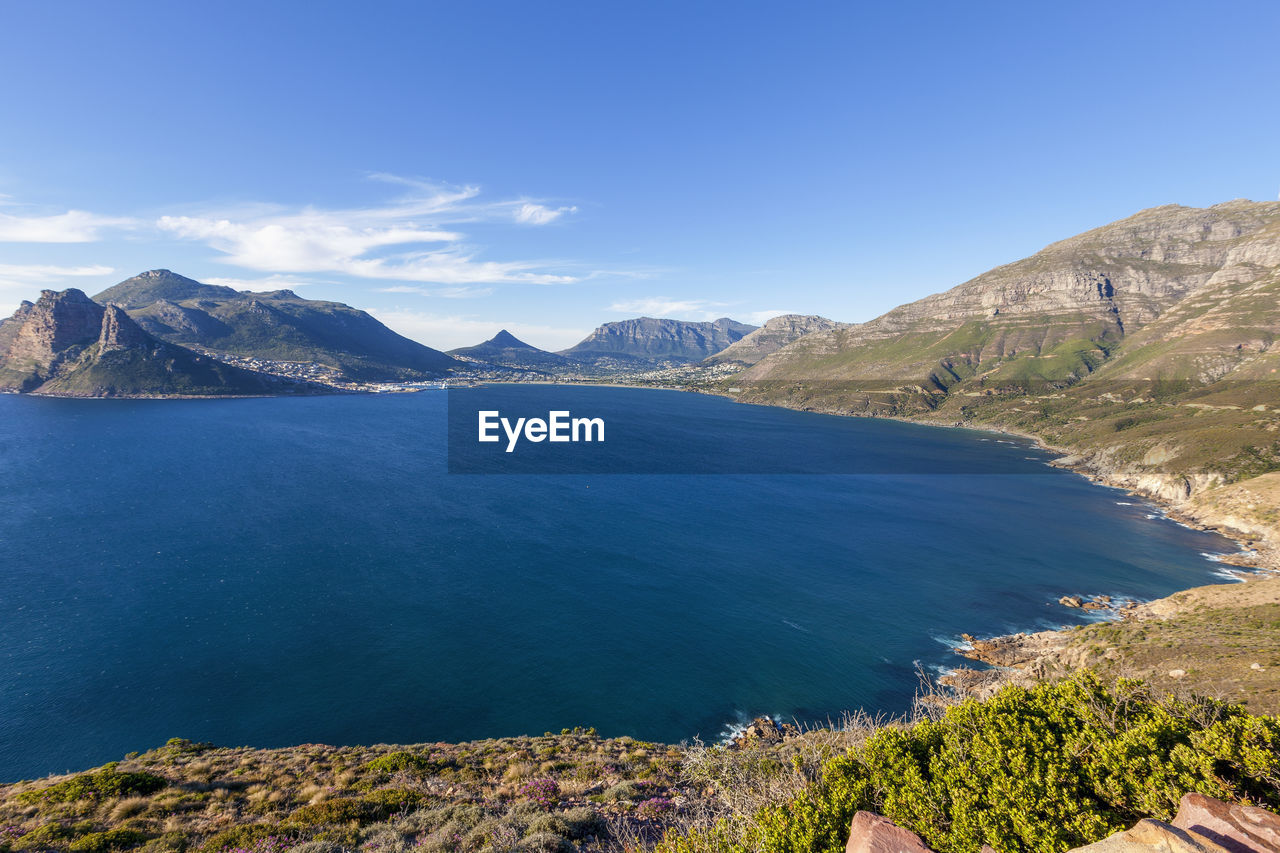 Scenic view of sea and mountains against blue sky