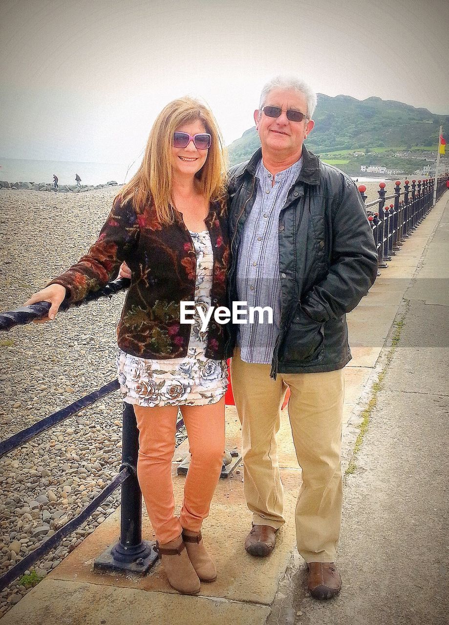 Portrait of couple standing by railing on road