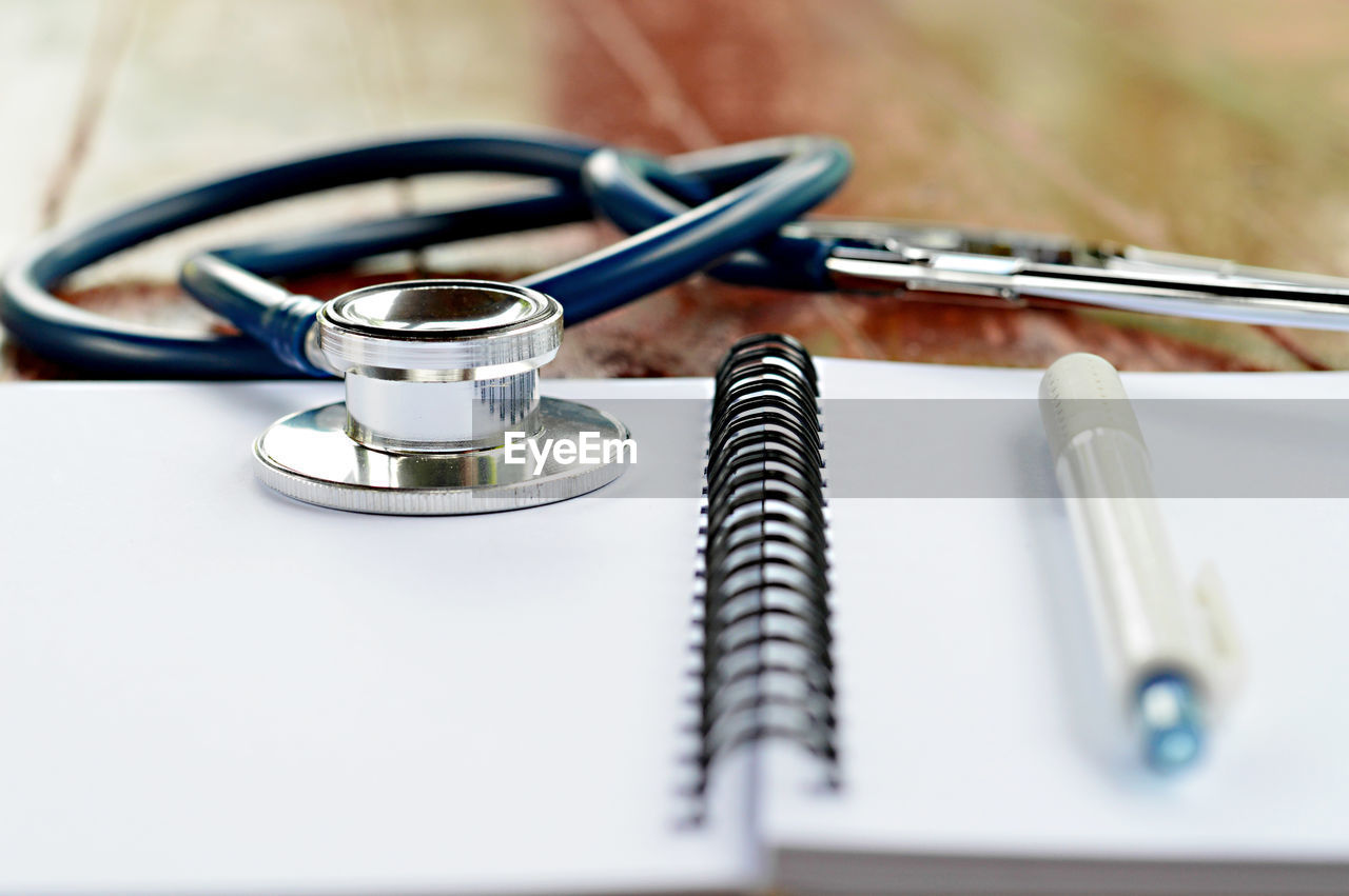 Close-up of stethoscope with spiral notebook on table