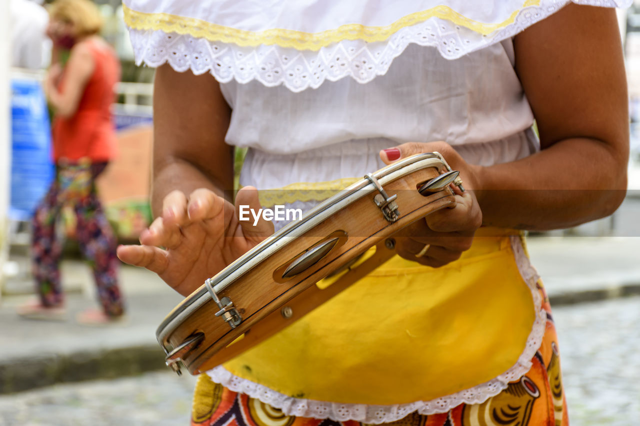 Woman in colorful ethnic clothes playing tambourine during a samba performance in salvador, bahia