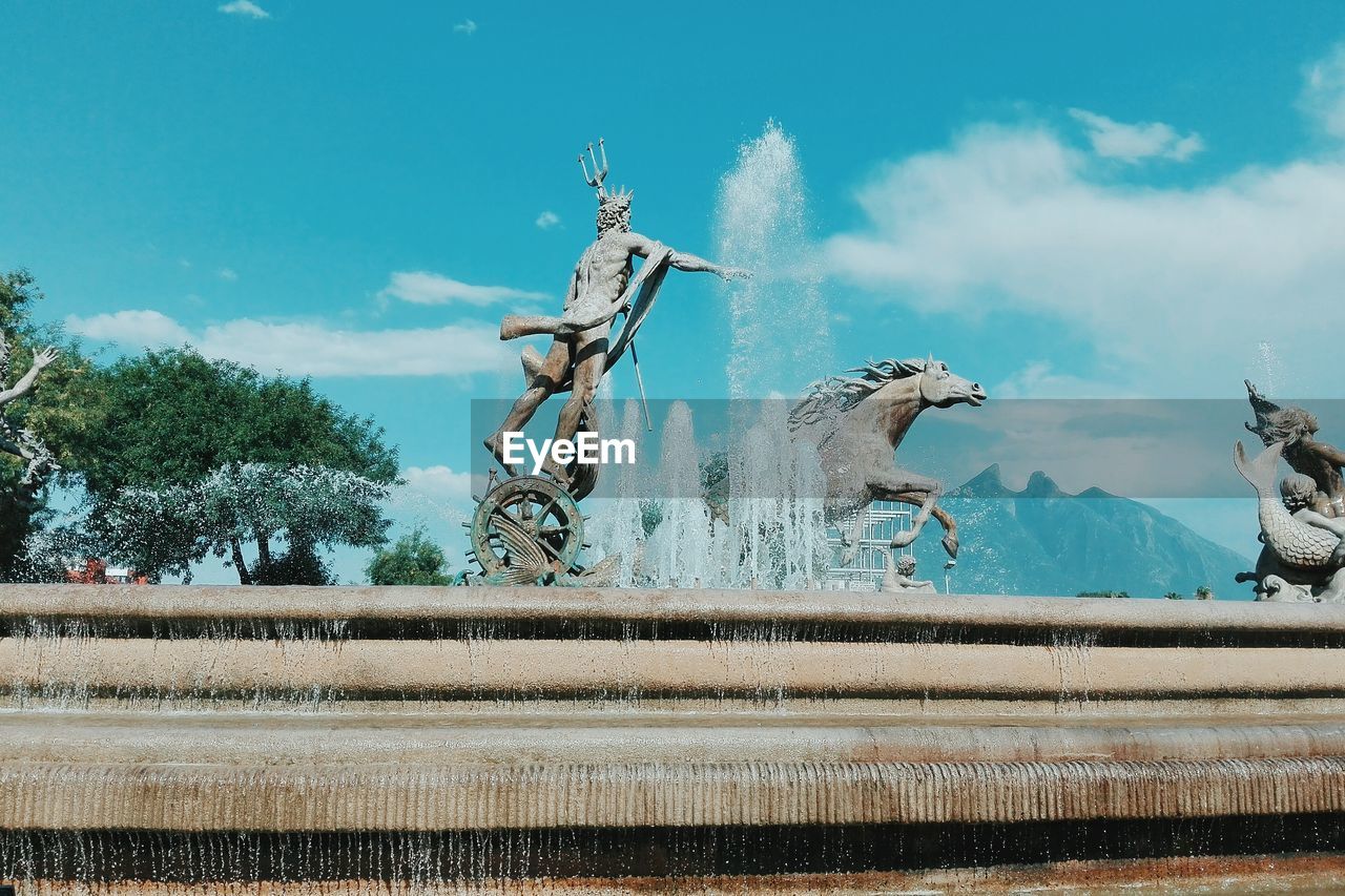 LOW ANGLE VIEW OF STATUE BY WATER AGAINST SKY