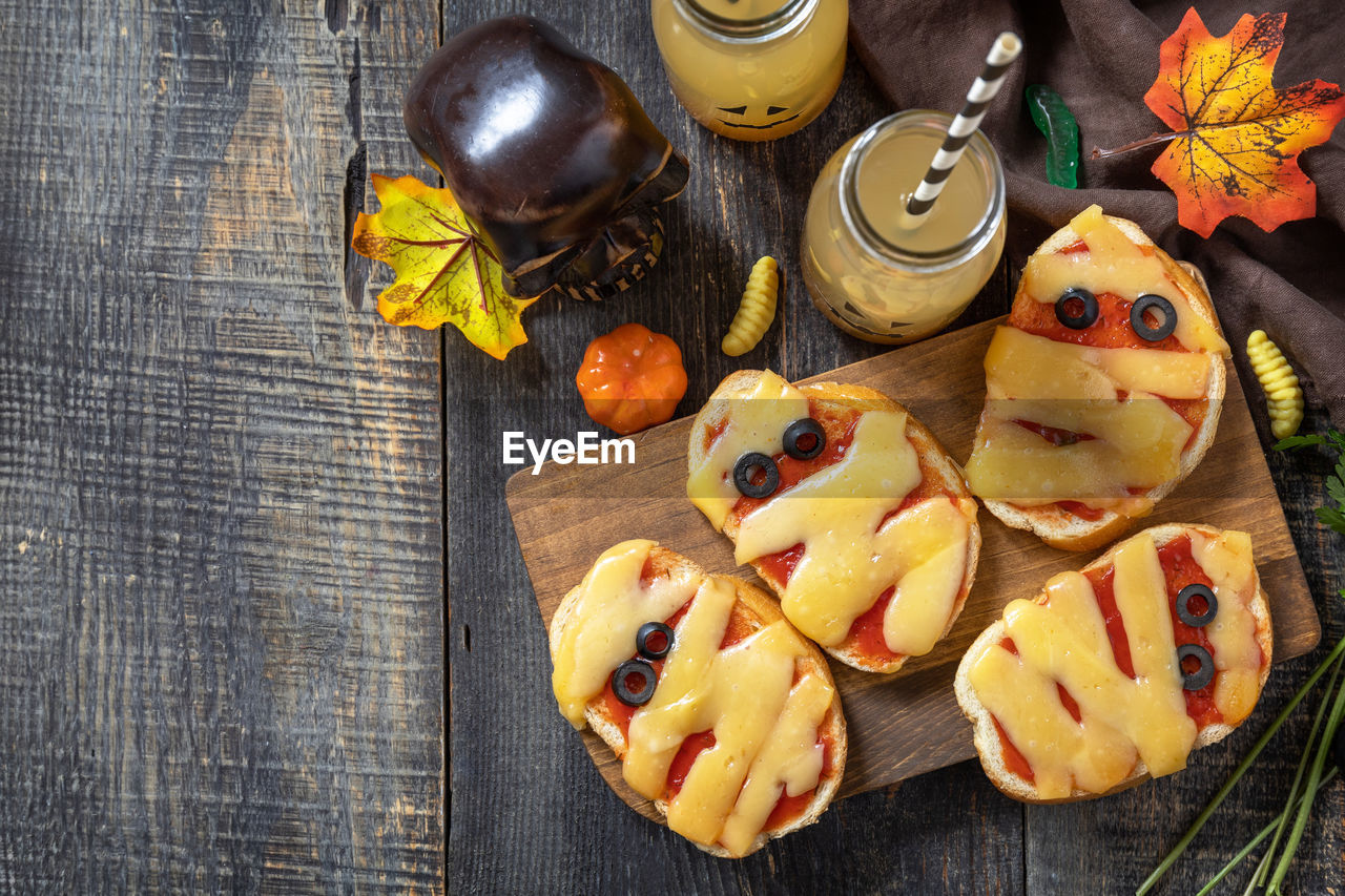 Halloween party food. halloween mummies mini pizzas on a wooden table. top view flat lay background.