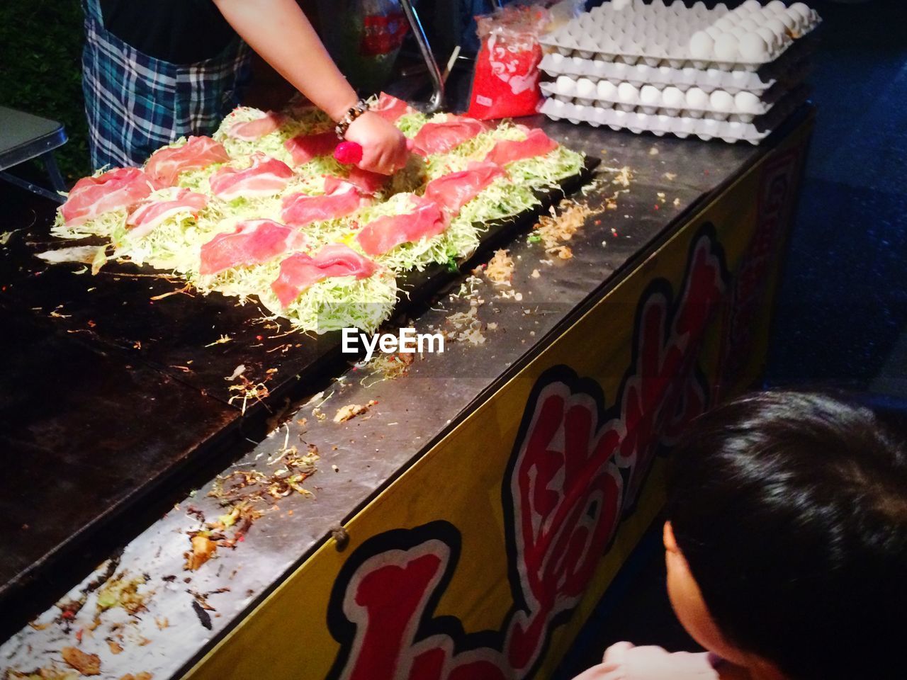 High angle view of child looking at vendor making snack at night