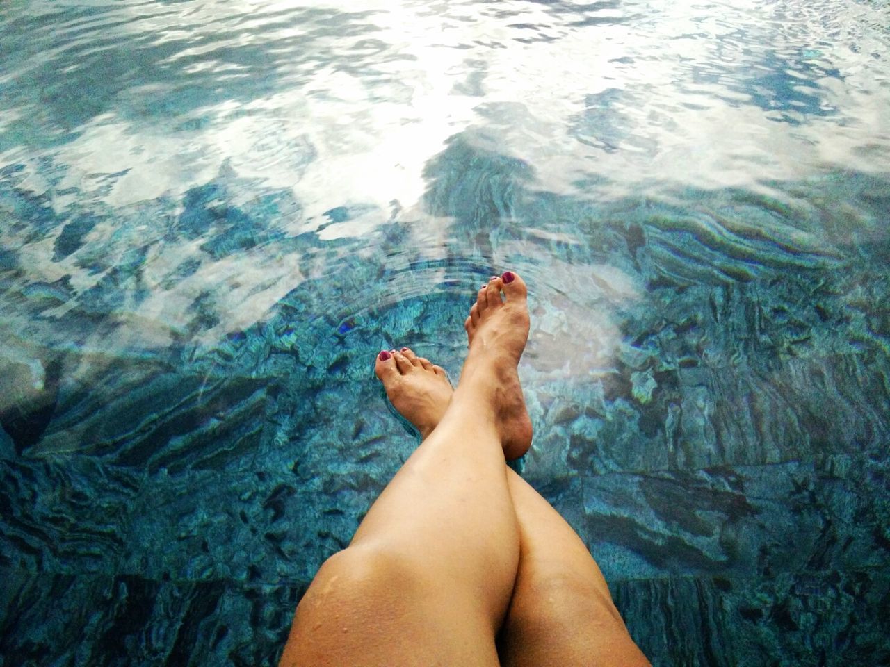 Low section of legs at blue rippled water