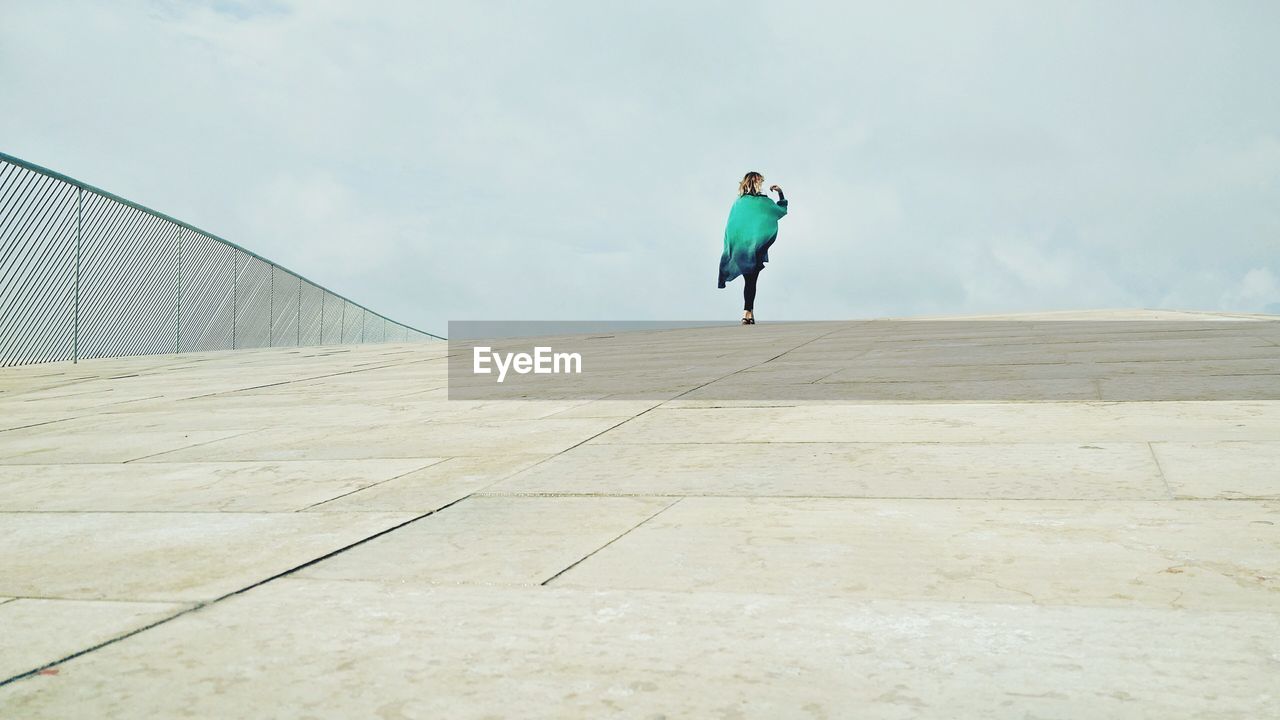 Full length of woman walking on bridge against sky