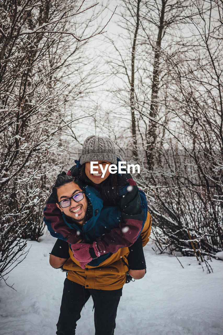 Portrait of smiling young couple against bare trees in forest