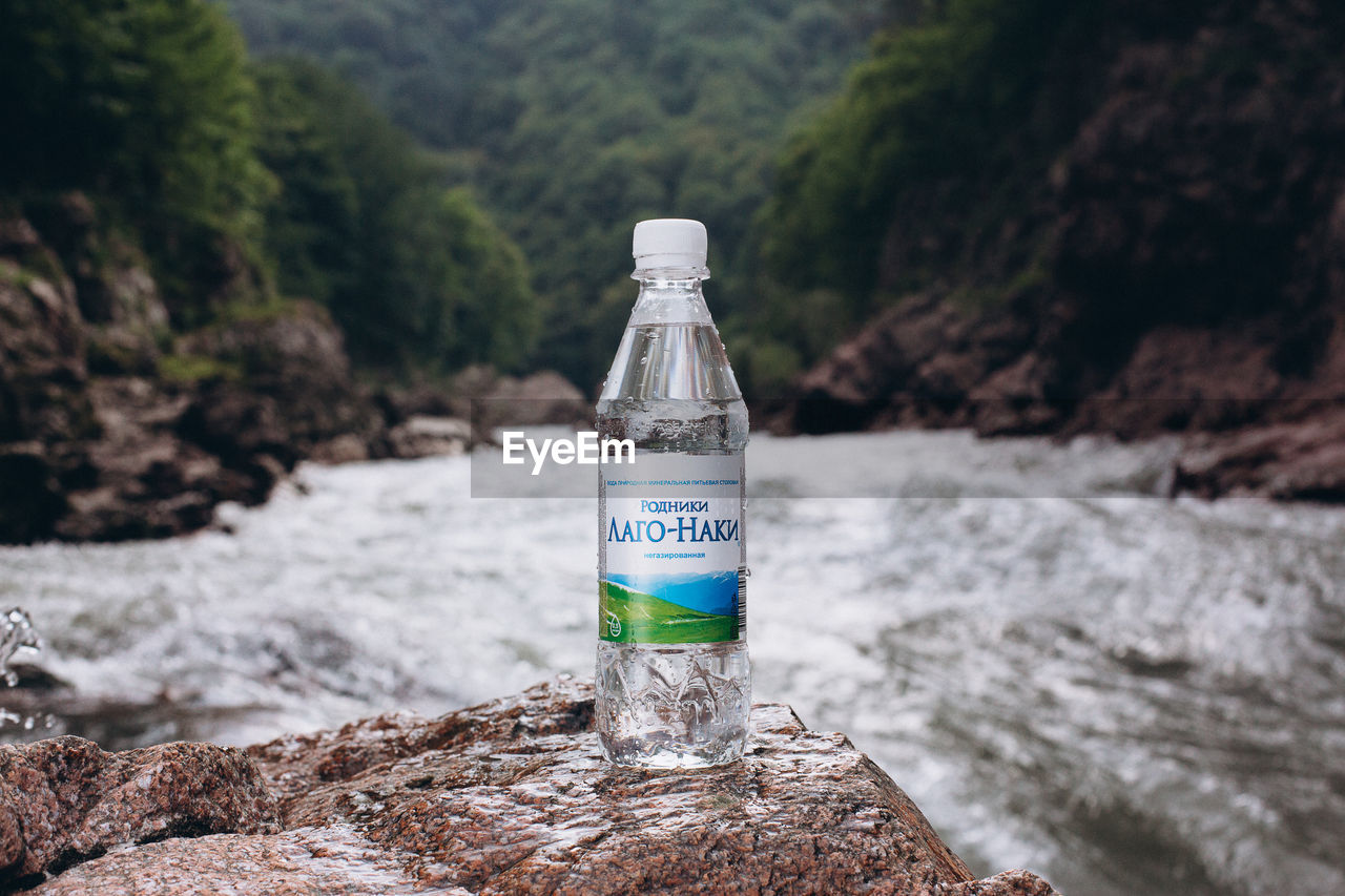 CLOSE-UP OF BOTTLE ON ROCK