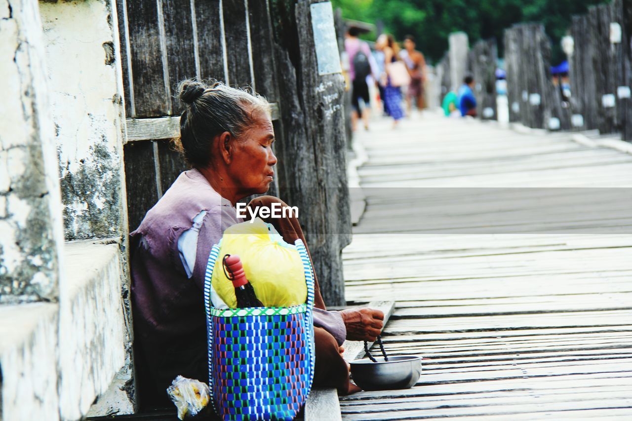 Side view of mature woman begging on pier