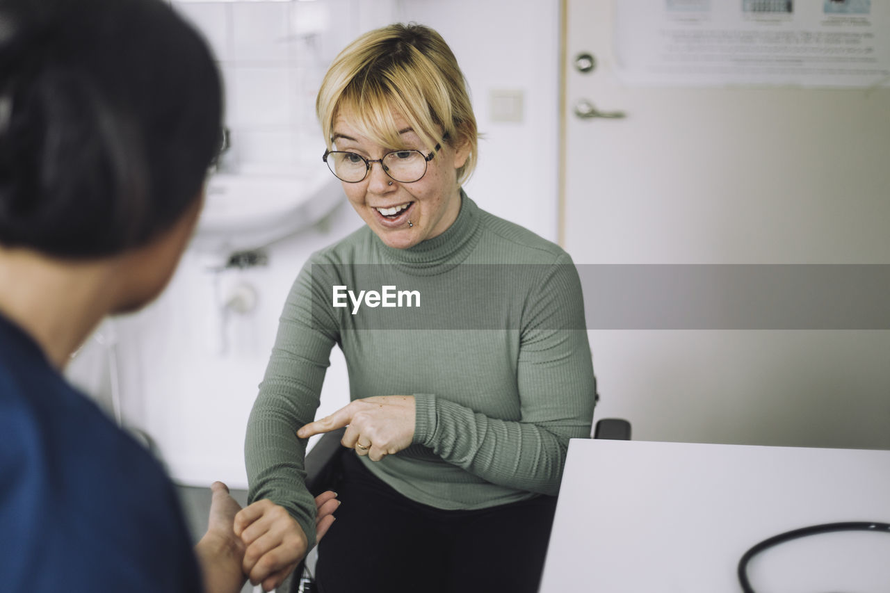 Woman with disability discussing with nurse during visit at hospital