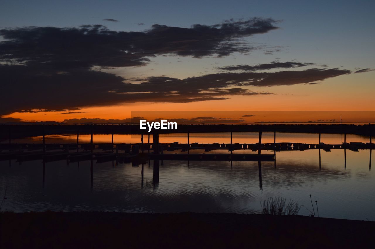 SILHOUETTE PIER ON LAKE AGAINST SKY AT SUNSET