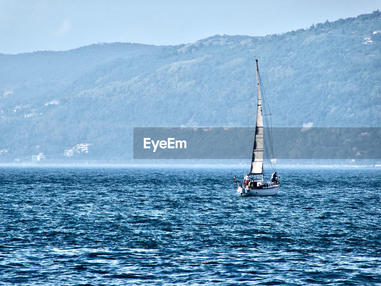 Sailboat moving on river against mountain