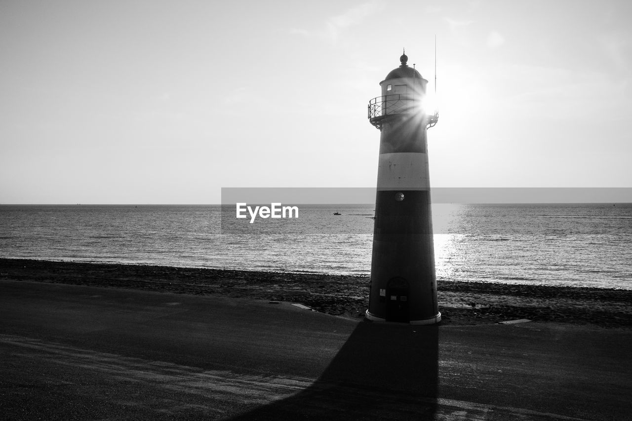 Lighthouse by sea against sky