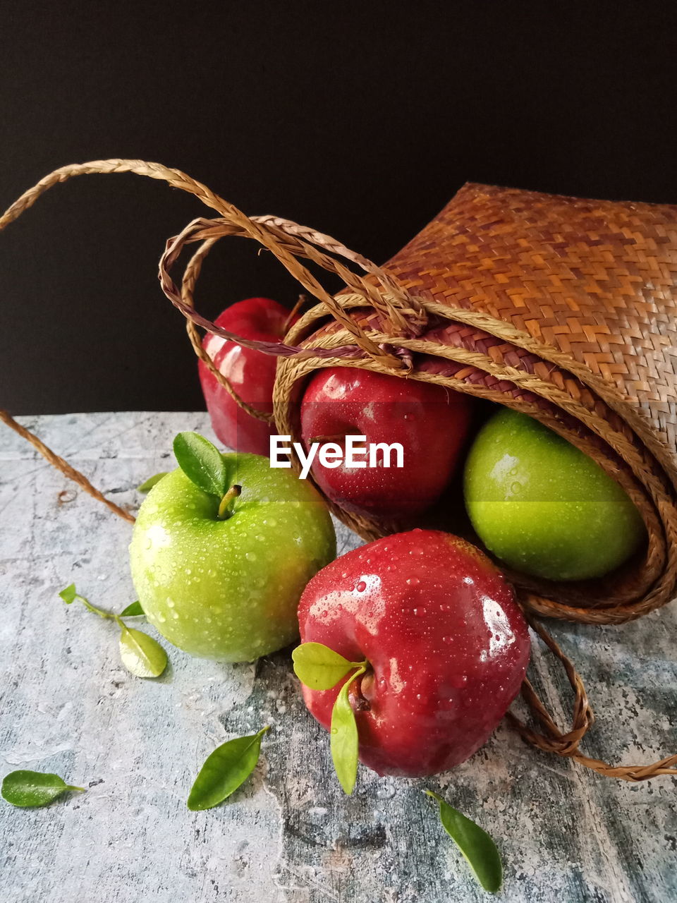 Close-up of apples in basket on table against black background