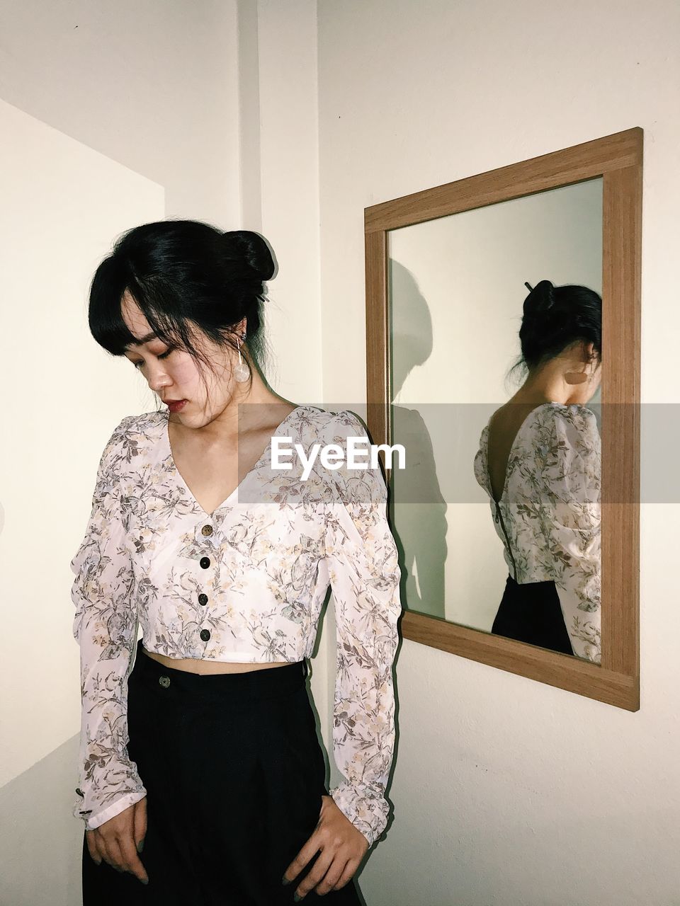 Portrait of woman looking away while standing in front of mirror 