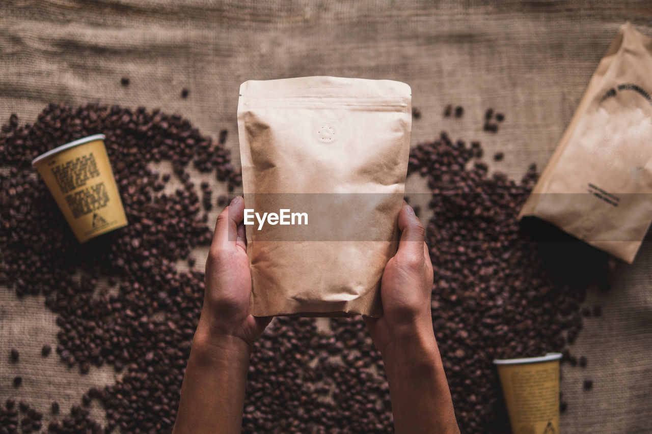 Cropped hand holding package over coffee beans