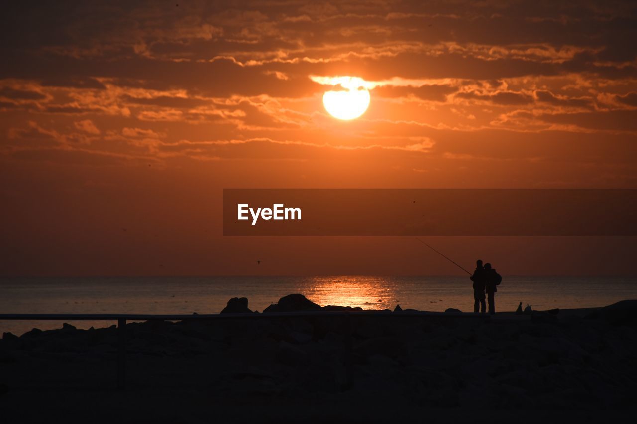 Silhouette of people on beach at sunset