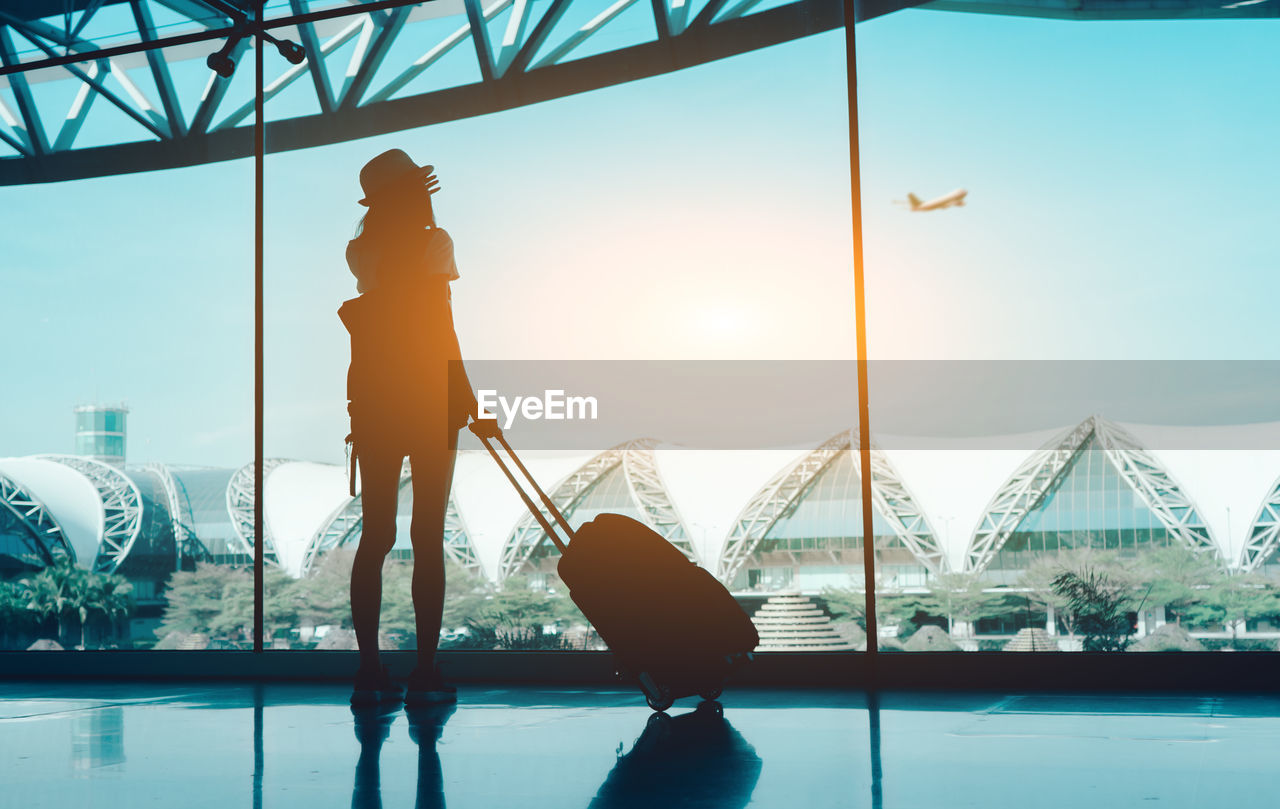 Silhouette woman with luggage standing in airport