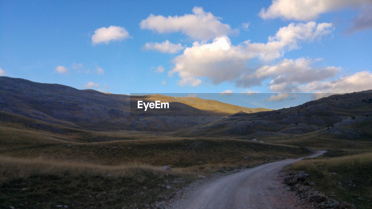 Road leading towards mountains against sky