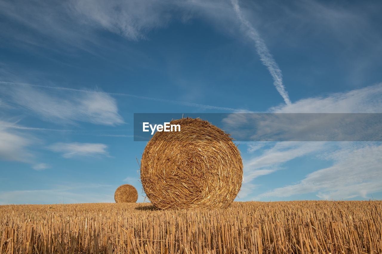 Hay bales on field against sky