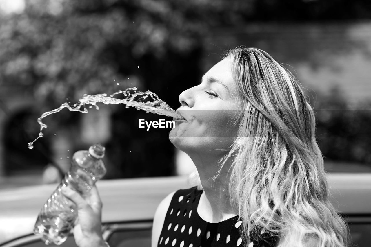 Close-up of woman spitting water during sunny day