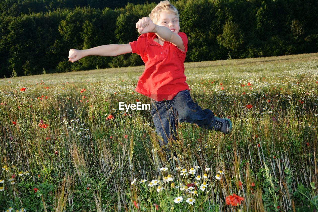 Portrait of boy jumping on grassy field