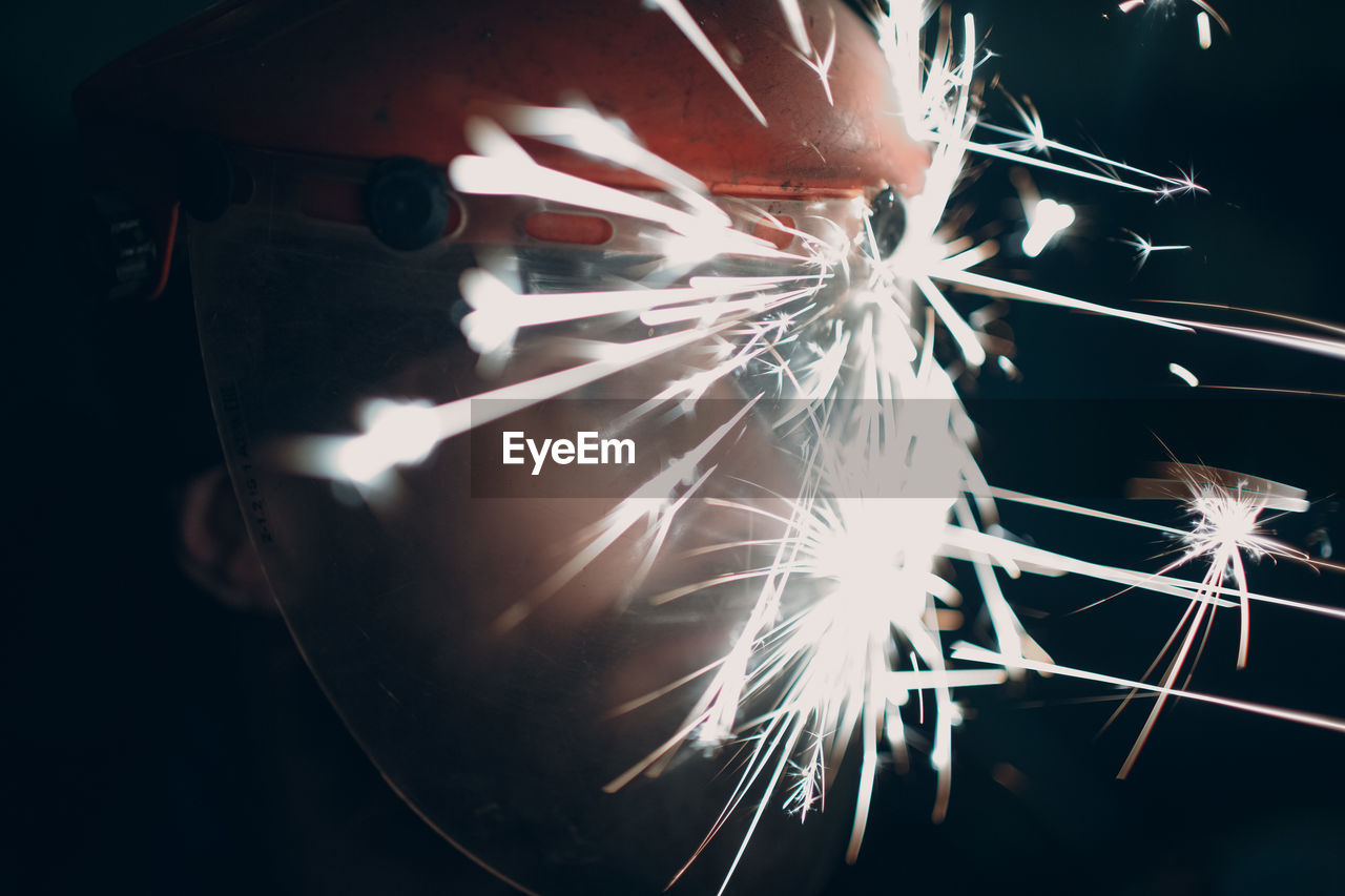 Close-up of sparks on working wearing helmet