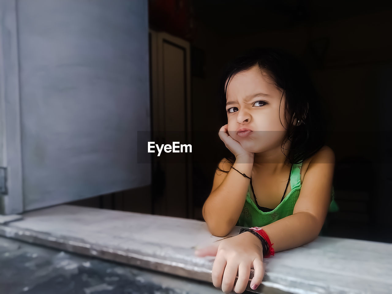 Portrait of cute girl sitting by window at home