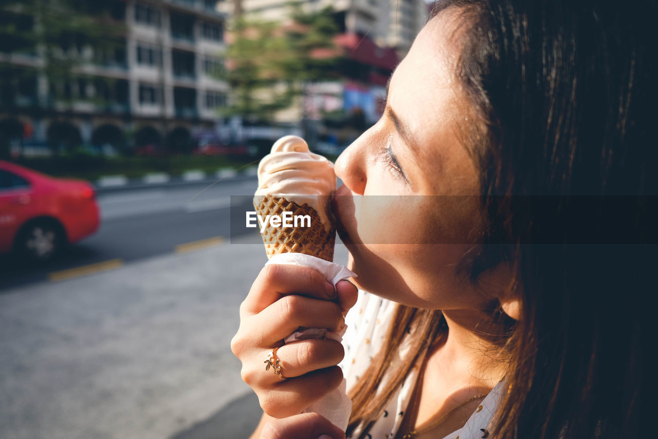 Woman eating ice cream cone in city