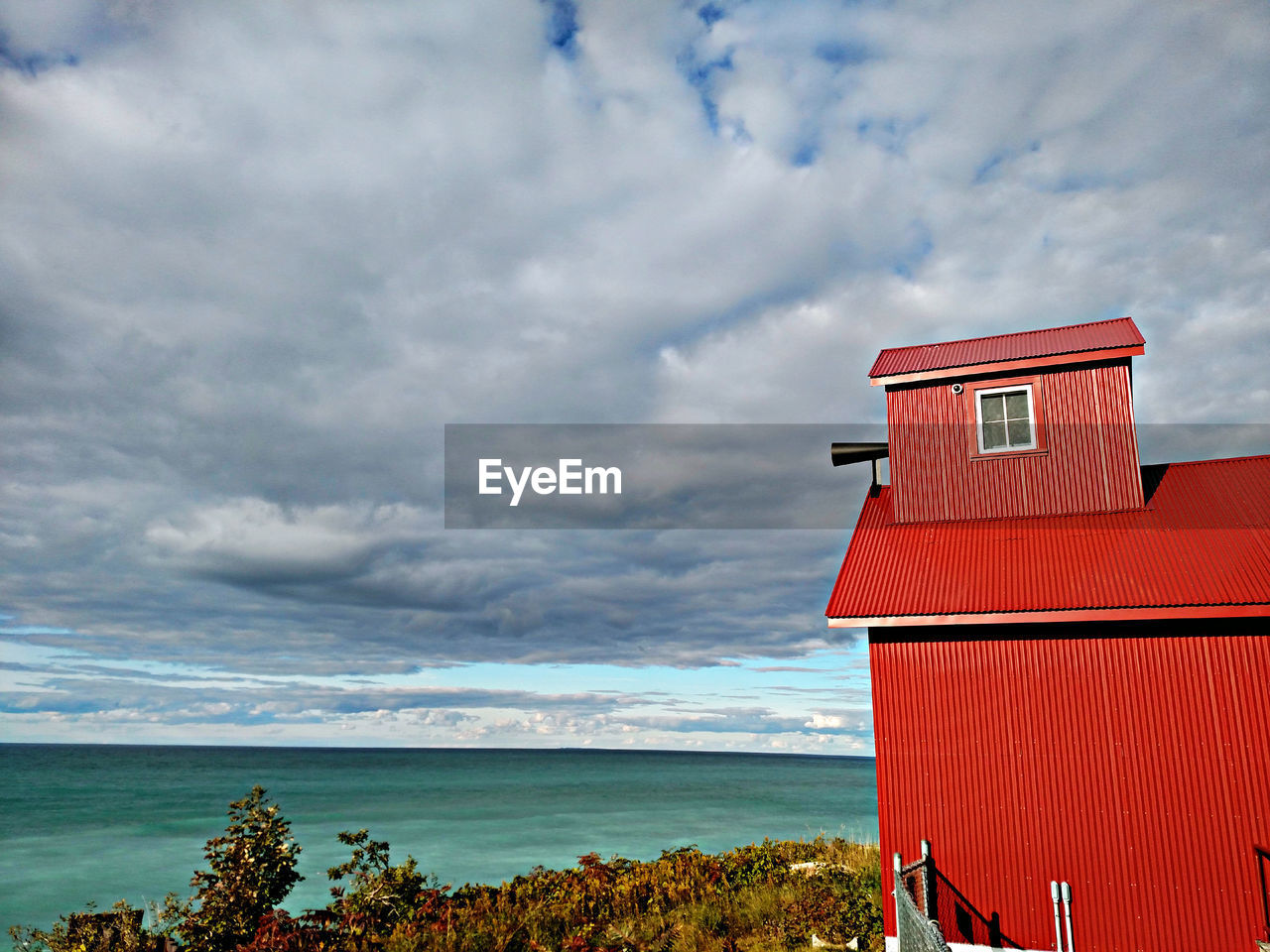 Red hut at beach against sky