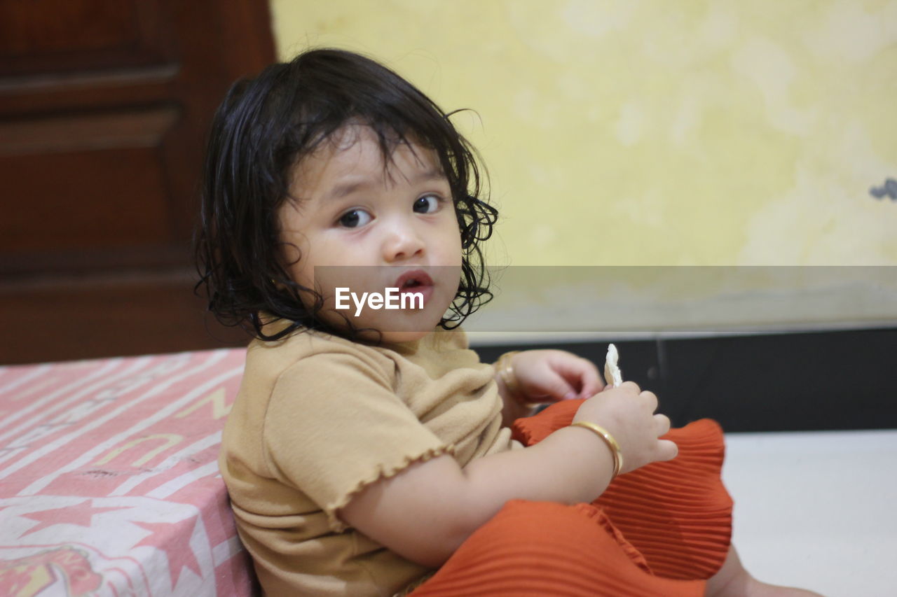 CUTE BABY BOY SITTING ON SOFA AT HOME