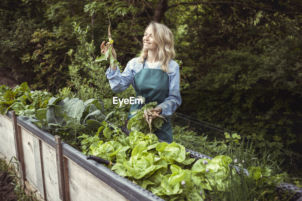 WOMAN STANDING IN FRONT OF PLANTS AND GREEN LEAVES