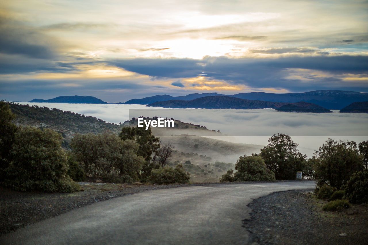 Scenic view of road by mountains against sky