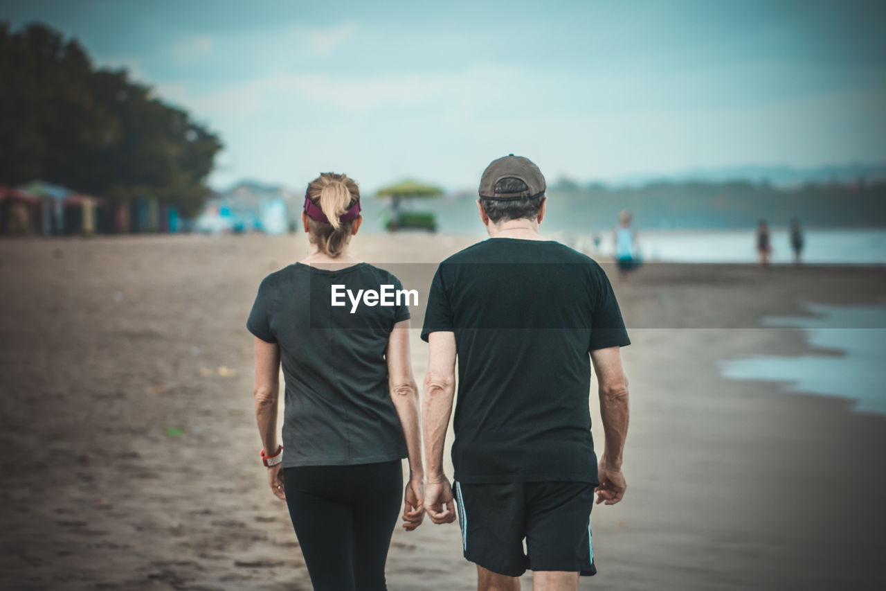 Rear view of couple walking at beach