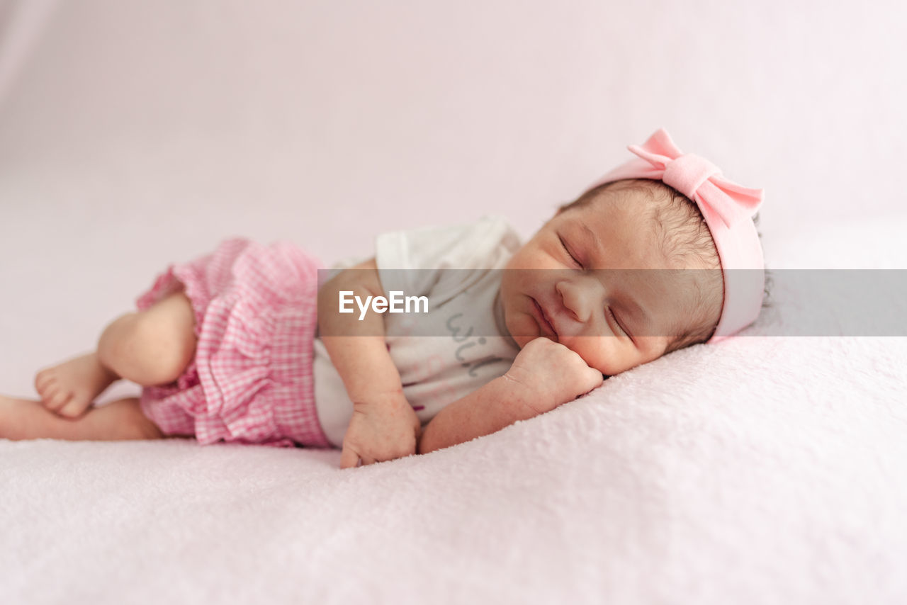 A newborn baby girl with a headband sleeping peacefully. newborn session concept