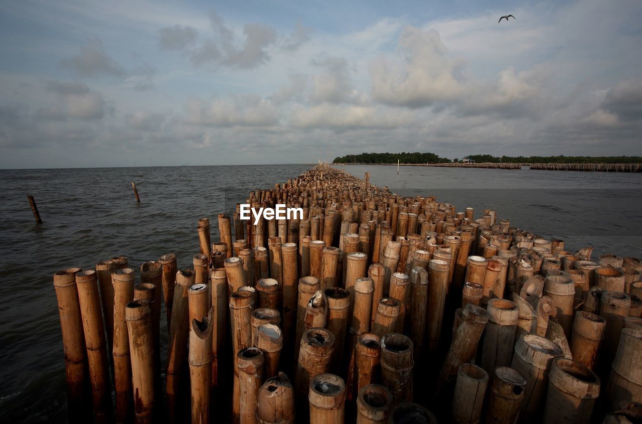 Wooden posts in sea against sky