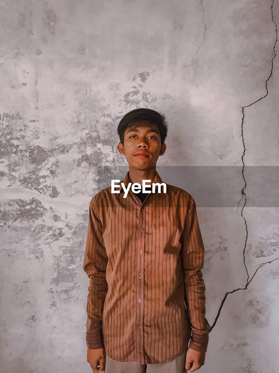 Portrait of young man standing against wall