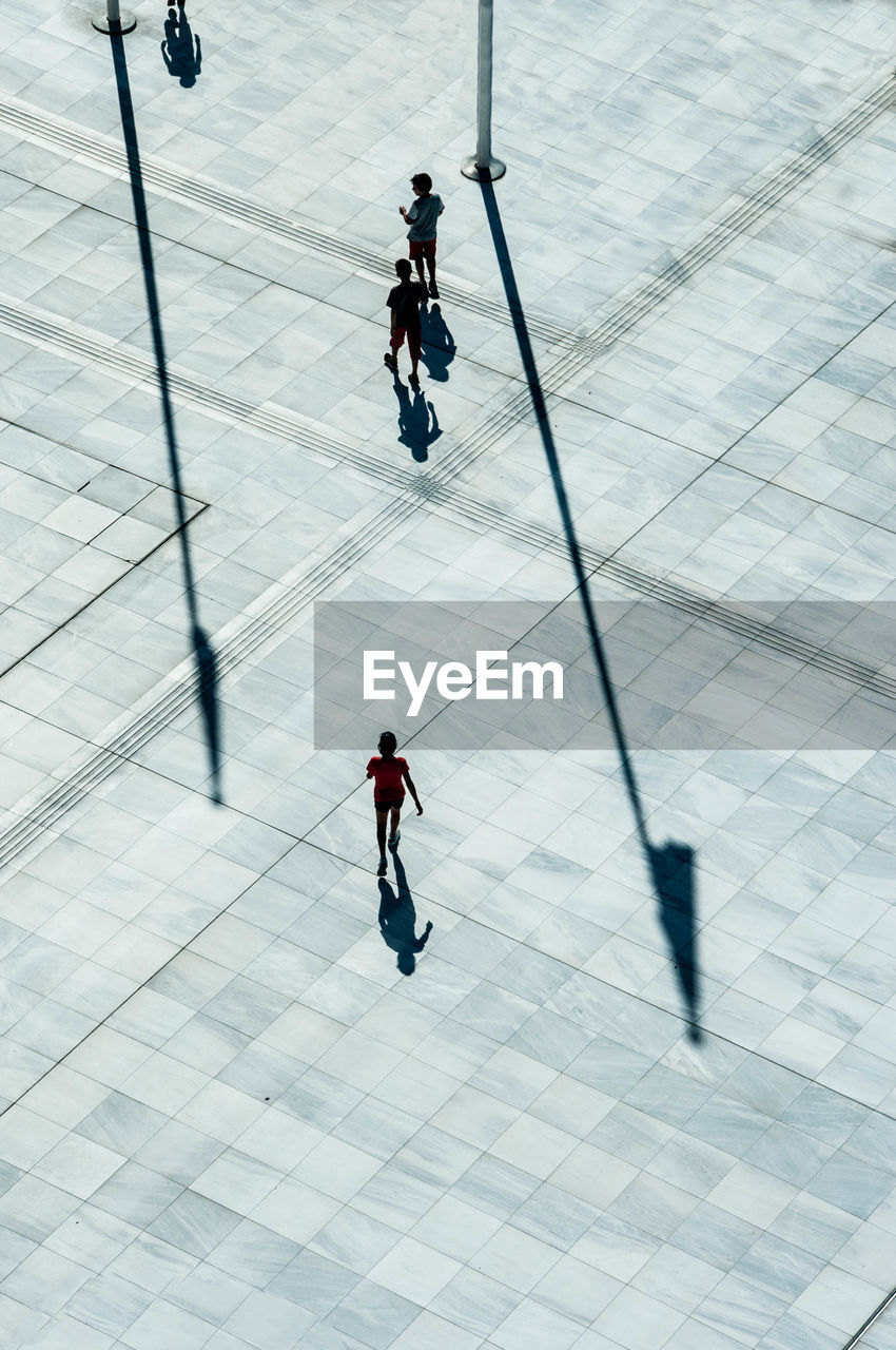 HIGH ANGLE VIEW OF MEN WALKING IN TILED FLOOR