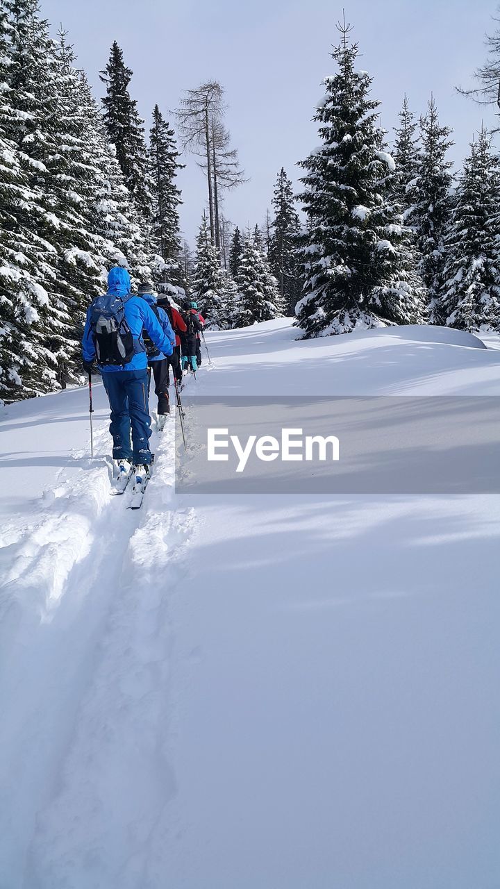 PEOPLE SKIING ON SNOW COVERED LAND