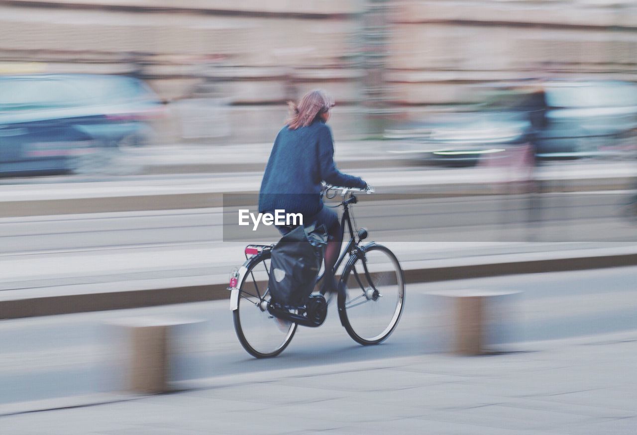 Woman riding bicycle on road in city