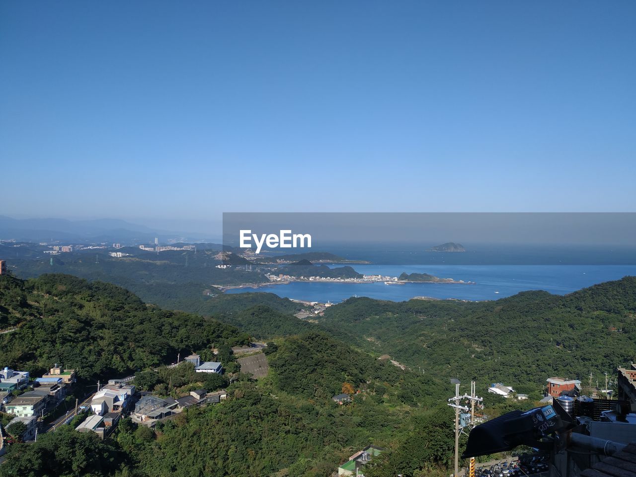 High angle view of townscape by sea against blue sky