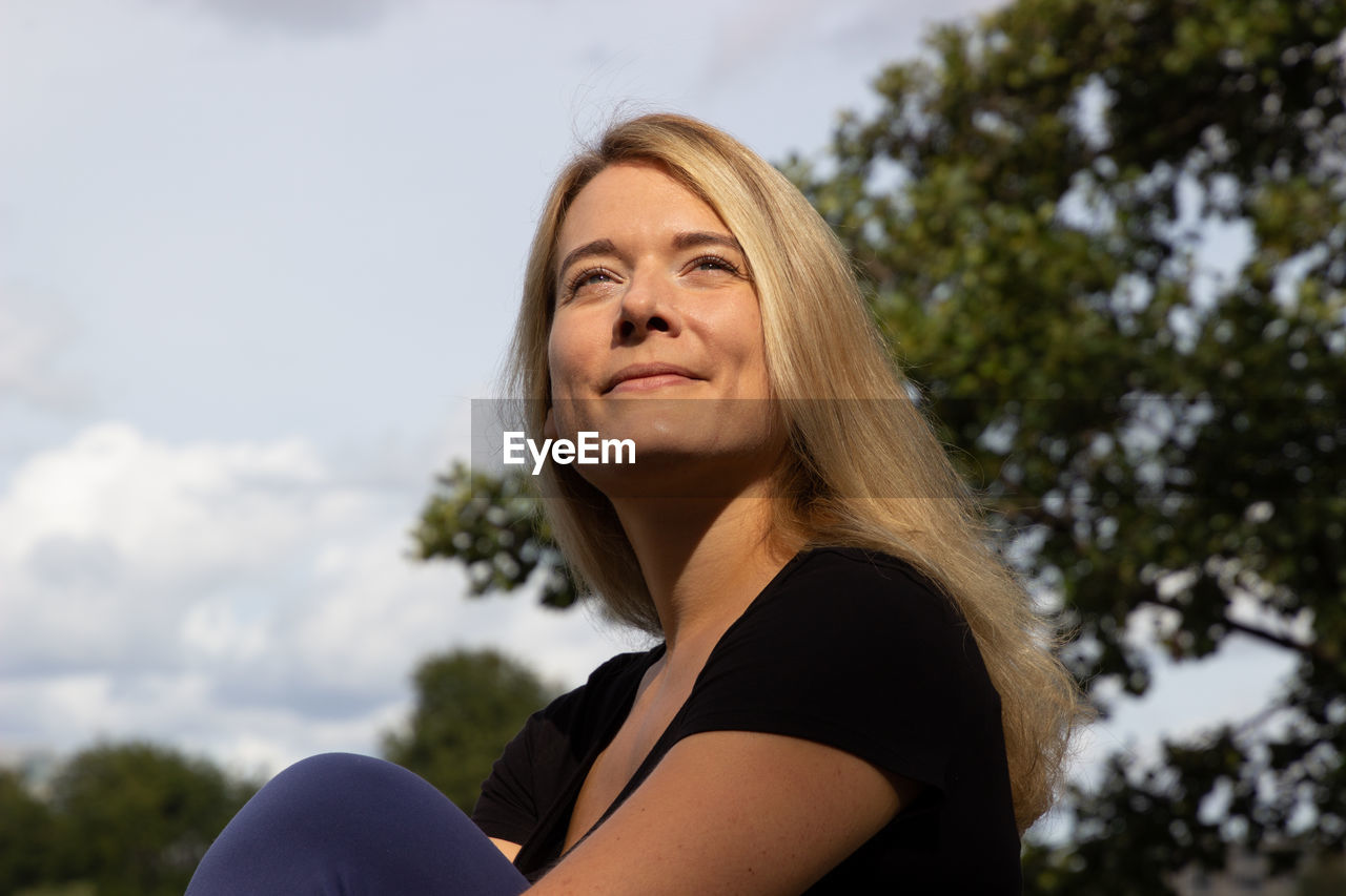 Portrait of smiling woman against sky