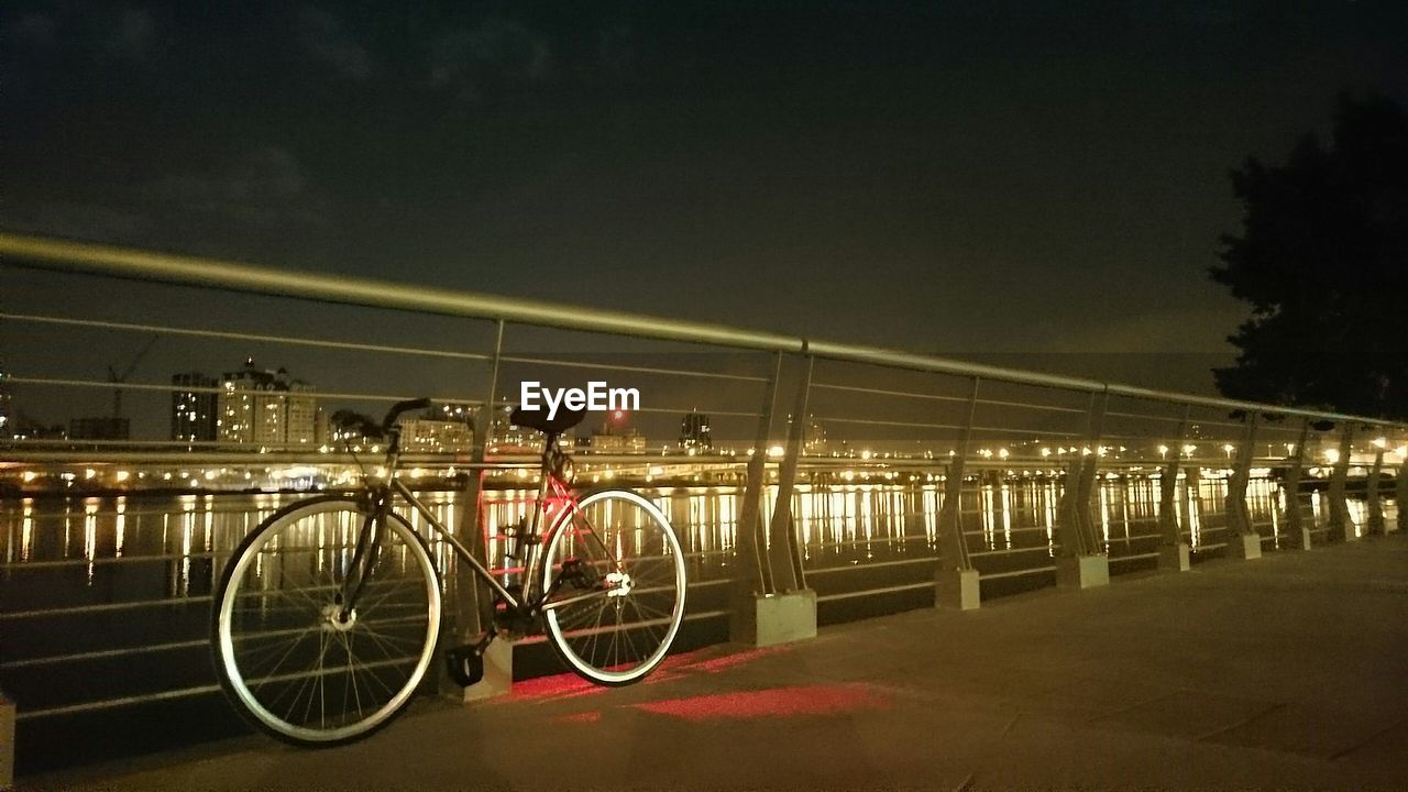 Bicycle parked by railing against sky