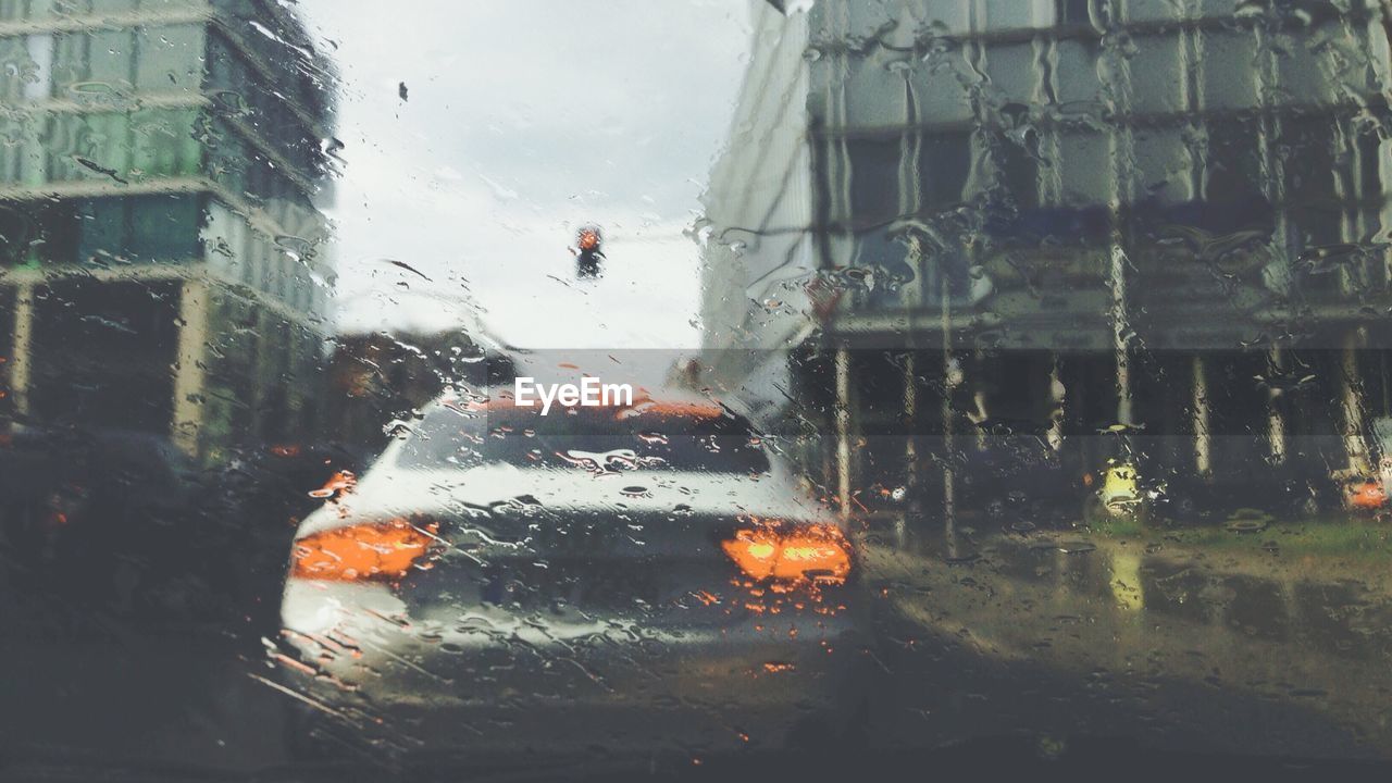 Car on city street in rain seen from wet windshield